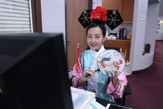 身著清宮古裝的華興保險員工在座位上手持團扇