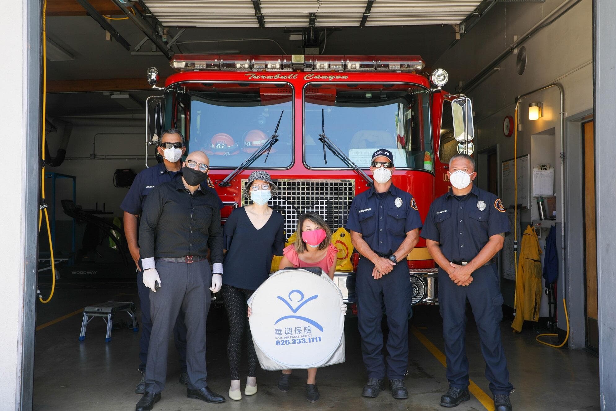 Firefighters and visitors with the KCAL Insurance sign in front of a fire engine