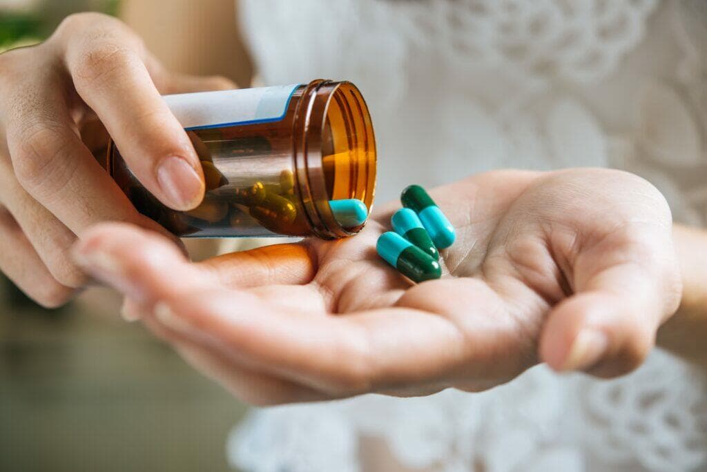 一名女性將處方藥瓶裡的膠囊倒在掌心