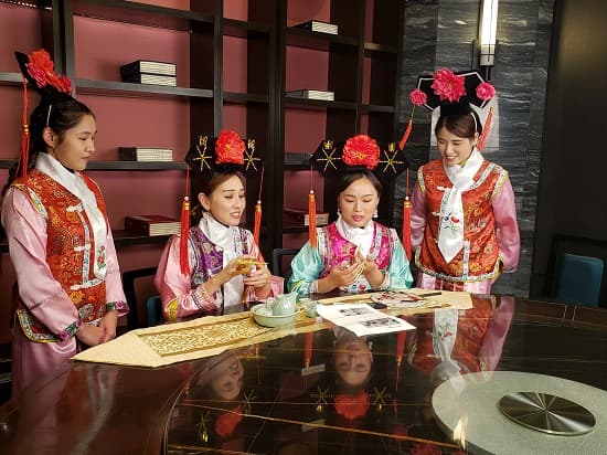 身穿清宫服饰的演员围坐茶桌，拍摄华兴保险广告