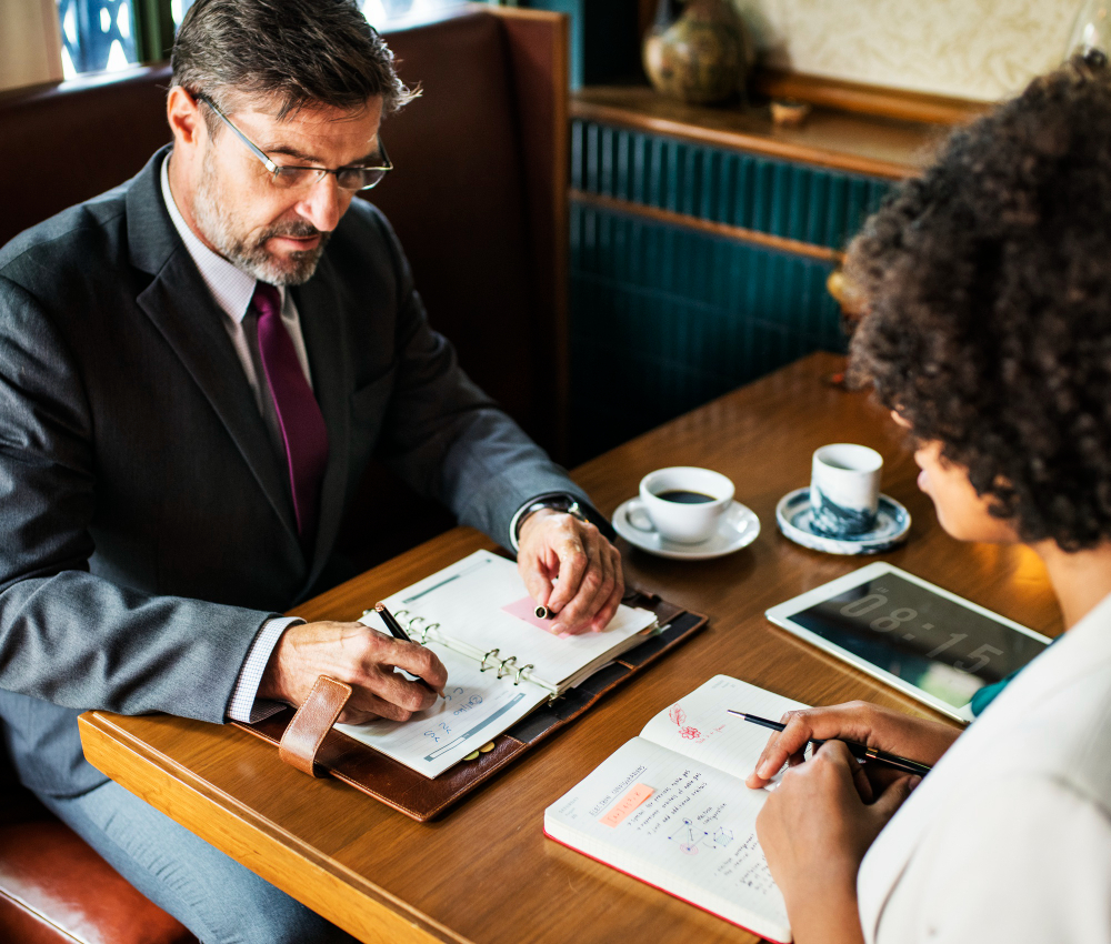 The photo shows a business man is talking with a business woman about their business performance